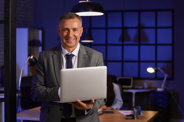 Male business analyst working with laptop in office at night. Data science concept