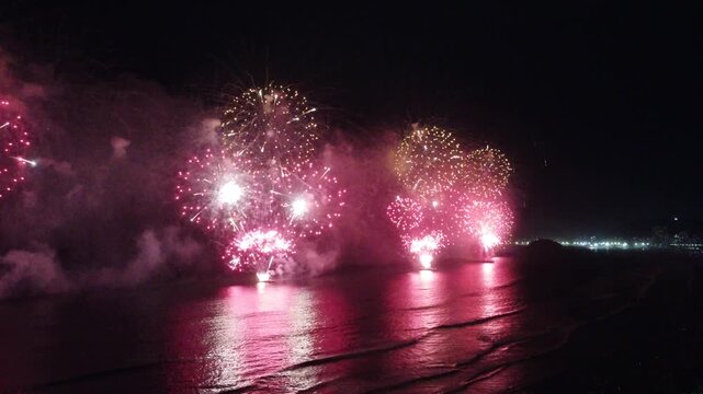 Fireworks display over the water at night.