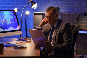 Male business analyst with clipboard working in office at night. Data science concept