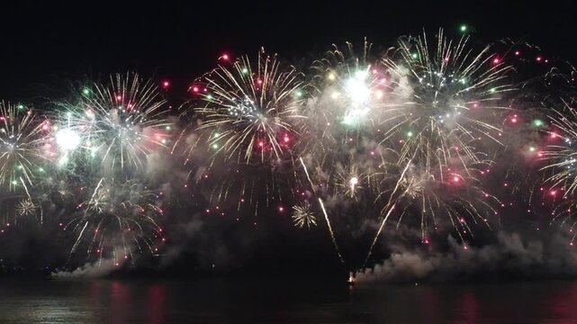 Fireworks display over the water at night.