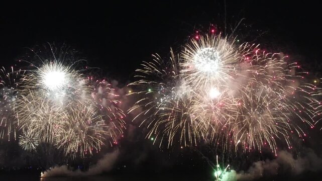 Fireworks display over the water at night.