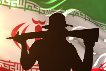 Silhouette of a fighter with a machine gun against the background of the Iranian flag in a bright backlight.