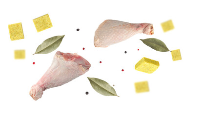 Bouillon cubes, chicken drumsticks, dry bay leaves and peppercorns flying in air on white background