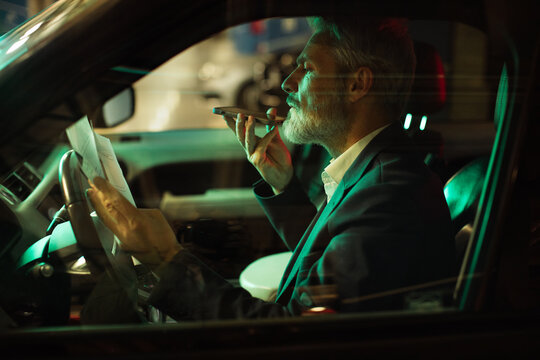 Mature man focused using voice assistant in car at night
