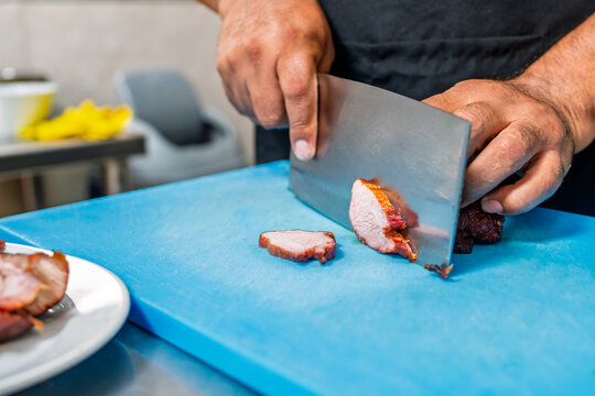 Chef slicing chifa char siu pork in kitchen