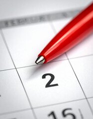 Bright red pen rests on a paper calendar highlighting the second day of february month clearly.