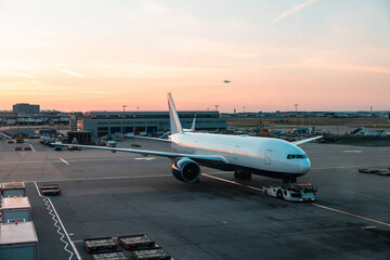 Commercial airplane on airport tarmac at sunset