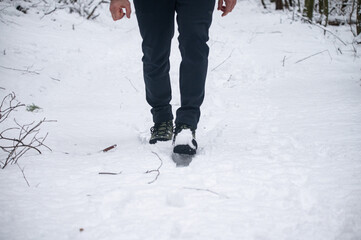 Hiking boots walking through fresh snow in winter landscape