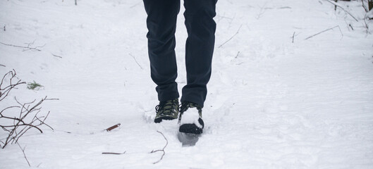 Hiking boots walking through fresh snow in winter landscape