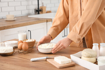 Young woman with different dairy products on table in kitchen