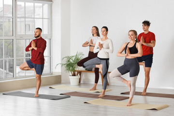 Fototapeta premium Group of sporty young people doing yoga in gym