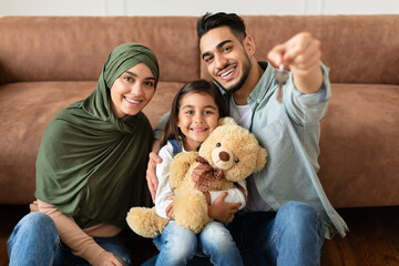 House Ownership. Happy Muslim Family Showing Keys, Cheerful Parents Hugging Little Kid Who Holding...