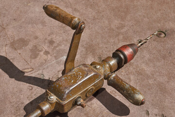 Vintage metal hand drill with wooden elements and visible wear. Traditional manual drilling tool representing craftsmanship, repair work, and historical technology.