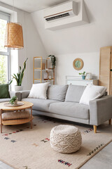 Interior of light living room with mirror, grey sofa and table