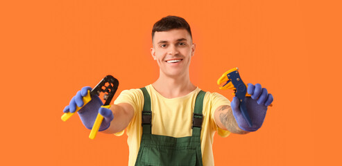 Young male electrician with wire crimper and stripper on orange background