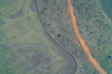 Long anti-tank ditch dug in a green field: aerial view of a military fortification line. Concept of defense and heavy armored vehicle barrier