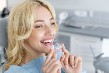 Invisalign orthodontics, modern dentistry concept. Happy young attractive blonde woman holding...