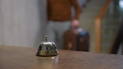 Male guest with luggage ringing hotel service bell for check in