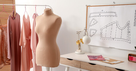 Interior of stylish atelier with mannequin, tailor's workplace and clothes rack