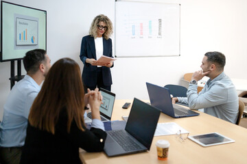 Businesswoman leading meeting presenting data to diverse team