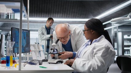 Woman working with microscope and sample tray in chemistry lab. Cellular investigation reflects the discovery process, medical research and nanotechnology for biotechnology solutions.