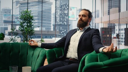 CEO practices mindfulness in his modern office listening to meditation music through a mobile app. Calm posture and closed eyes reflect a moment of peace amid corporate pressures. Camera A.