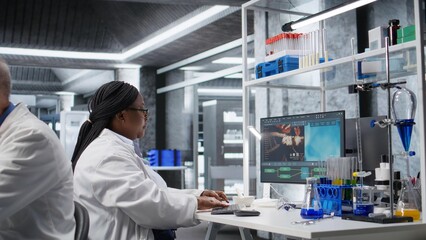 Black woman working in biotechnology lab surrounded by modern equipment. Research study for genetics, nanotechnology and healthcare data, supporting pharmaceutical science.
