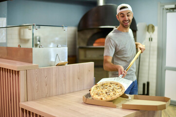 The chef is putting the pizza in the box. 