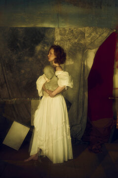 Side view of beautiful woman with statue in a dark room