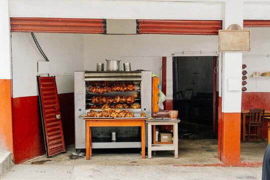 An image of an outdoor food stall with a large chicken rotisserie.