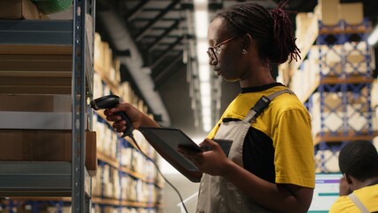 Black woman staff using a barcode scanner to process shipping labels on boxes from storage racks. Scanning awb tags for package tracking service with tracking info, accurate logistics. Camera B.