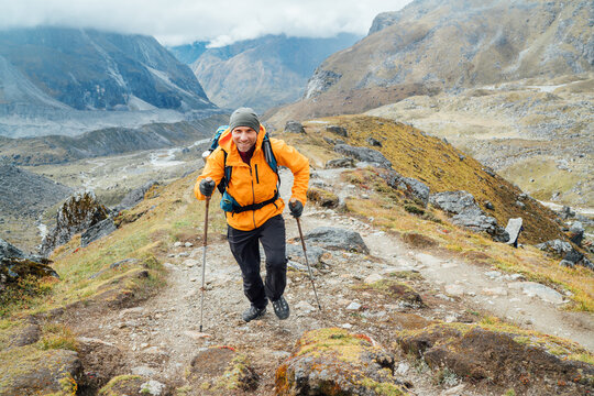 Caucasian man with backpack and trekking poles climbs by Makalu Barun Park route near Khare. Mera peak climbing acclimatization active walk. Backpacker enjoying valley view. Active people concept.