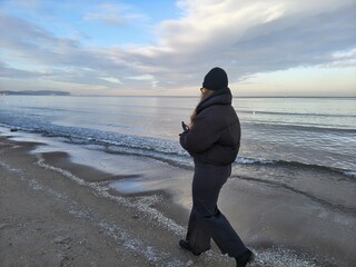 Kobieta spacerujaca brzegiem morza © EwaAF