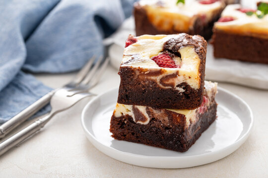 Brownies with cheesecake layer and raspberries cut on a board