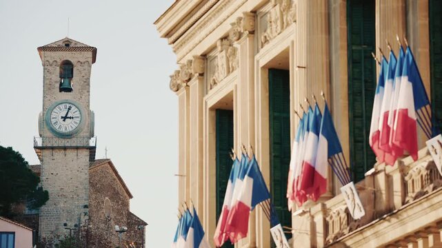 Wide shot of a historic building decorated with French tricolor flags under clear daylight