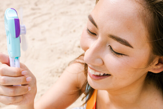 A woman cools herself with a hand-held fan