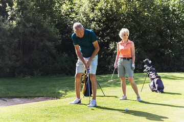 A senior couple playing golf on a sunny day