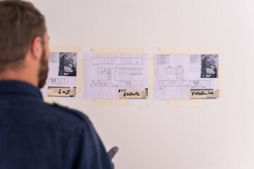 Worker studying blueprints on wall 