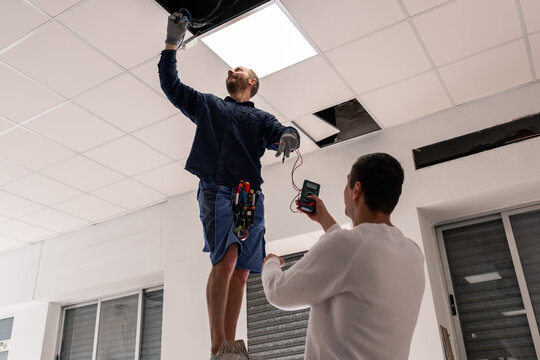 Men checking wiring at office using multimeter