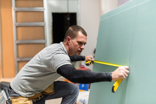 Focused man measuring gypsum board 