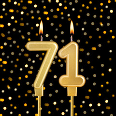 Number 71 birthday candle on a black background with blurred lights