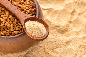 Methi Dana - Fenugreek seeds and powder in a wooden spoon and bowl