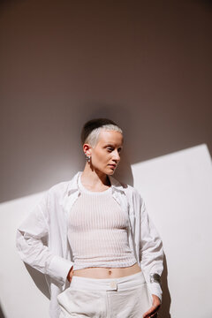 Young blonde woman poses in bright, minimalist room with sunlight