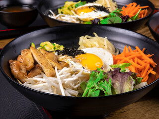 Ganjatang, Korean mixed vegetables on rice with poached egg and chicken in a black dish