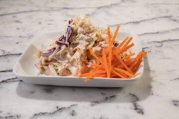 A fancy restaurant presentation of a square plate of coleslaw