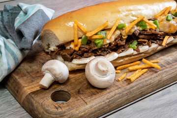 A cheese steak sandwich with mushrooms and matchstick potato fries