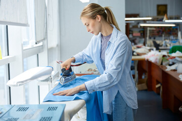 Craftswoman skillfully presses fabric, clothing artisan expertly ironing fabric