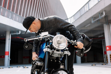 Mechanic adjusting engine on motorcycle in urban parking