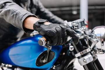 Close-up of a rider's hand gripping the throttle of a blue motorcycle