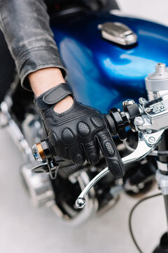 Rider grips motorcycle handle while wearing black gloves
